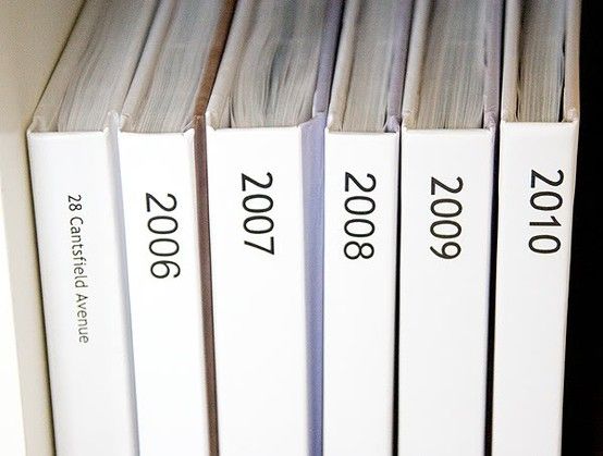 a row of white books sitting on top of a book shelf next to each other