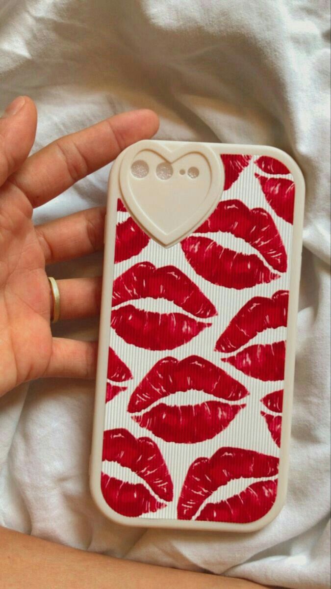 a person is holding a cell phone case with red lips on it and a heart in the middle