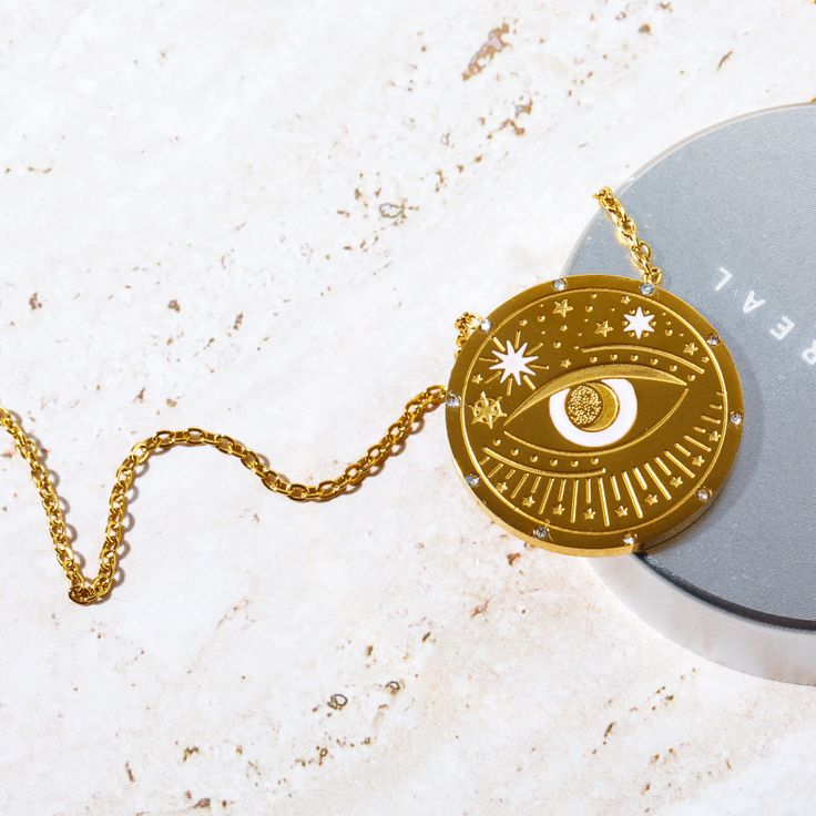 Our Celestial Coin Medallion Necklace—a captivating accessory inspired by the celestial wonders of the universe. This necklace features a stunning coin-shaped pendant crafted in gold, adorned with celestial motifs that evoke a sense of mystery and magic. With three distinct styles to choose from—moon phase, sun and moon, and evil eye—this necklace allows you to express your unique style while embracing the celestial energies that surround us. Symbolic Gold-plated Coin Necklace, Gold Mystical Necklace With Sun And Moon Design, Mystical Gold Necklace With Sun And Moon Design, Celestial Round Medallion Necklace For Gifts, Gold Plated Symbolic Medallion Necklace, Symbolic Gold-plated Medallion Necklace, Symbolic Gold Plated Medallion Necklace, Gold Necklace With Sun And Moon Design, Celestial Medallion Necklace Gift With Round Pendant