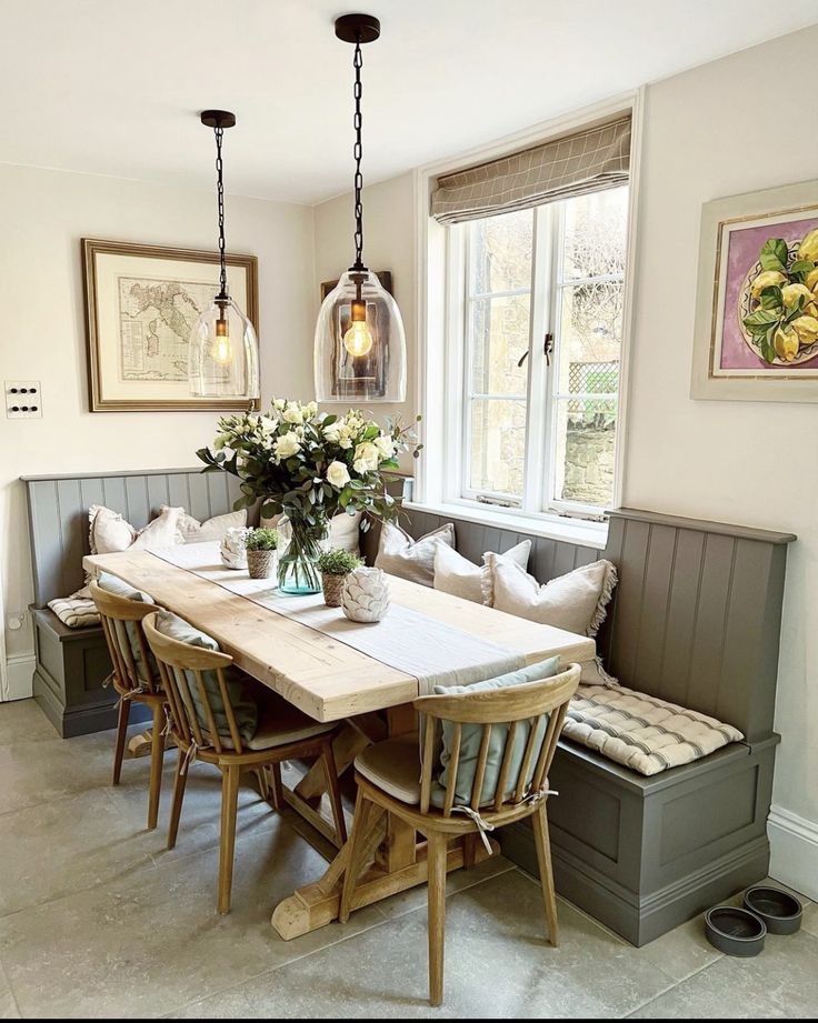 a dining room table and bench with flowers in vases on the centerpiece next to it