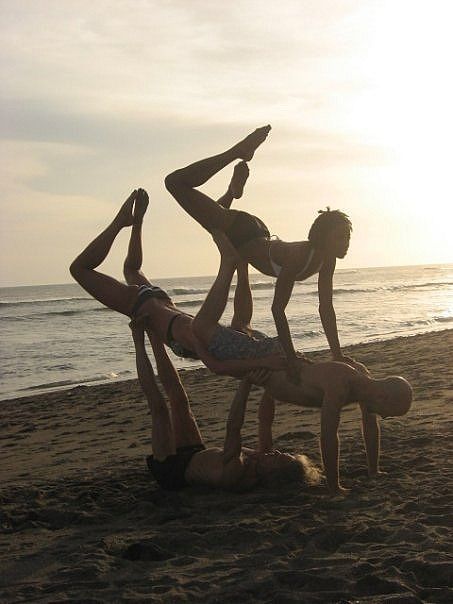 three people are doing yoga on the beach