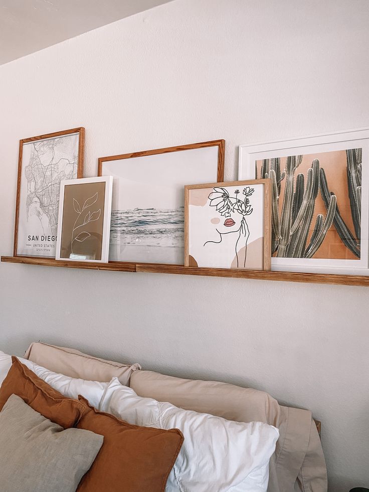 a bed with pillows and pictures on the wall above it, along with other items