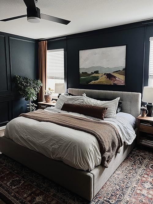 a large bed sitting in the middle of a bedroom next to a painting on the wall