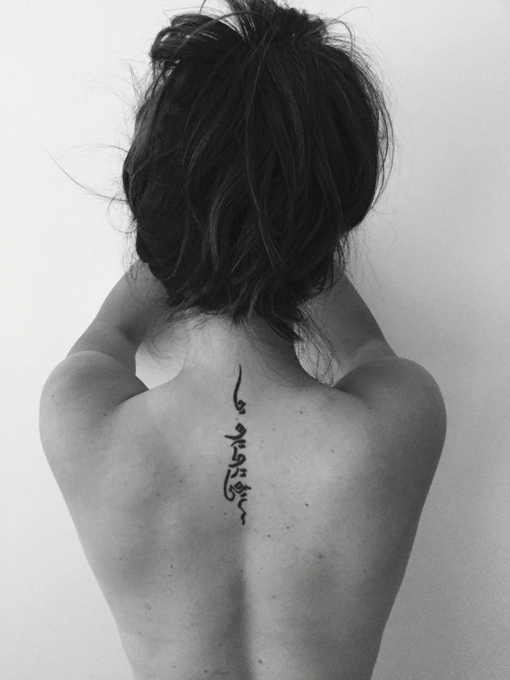 the back of a woman's neck with chinese writing on her lower back tattoo