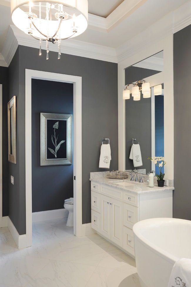 a bathroom with gray walls and white fixtures on the vanity, toilet and bathtub