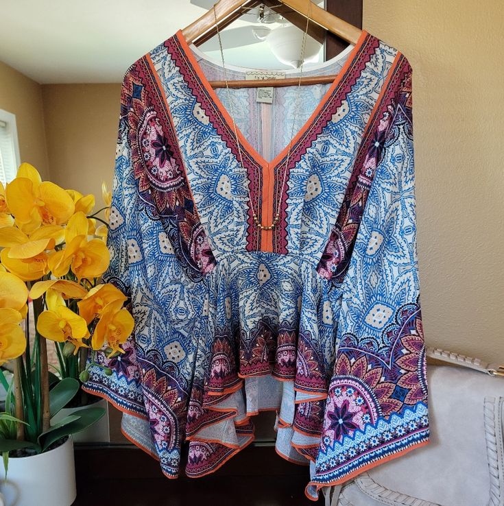 Nwot. All The Bohemian Vibes With This Gem. Colors Are Super Vivid. Deep V-Neck. Empire Waist With A Ruffle Hem. Sleeves Stop At Elbow And Flare Out. Looks Great With A Bralette, Distressed Shorts And Gold Accessories. Bust: 19-20 Inches (Approximate) Length: 23 Inches Shoulder To Hem Multicolor Floral Print V-neck Peasant Top, Patterned Flowy V-neck Blouse, Peasant Style V-neck Blouse For Brunch, Floral Print V-neck Peasant Top For Beach, Flowy Peasant V-neck Blouse, Bohemian Patterned V-neck Peasant Top, Flowy V-neck Peasant Top, Summer Patterned V-neck Blouse, Blue Vibrant Print V-neck Top