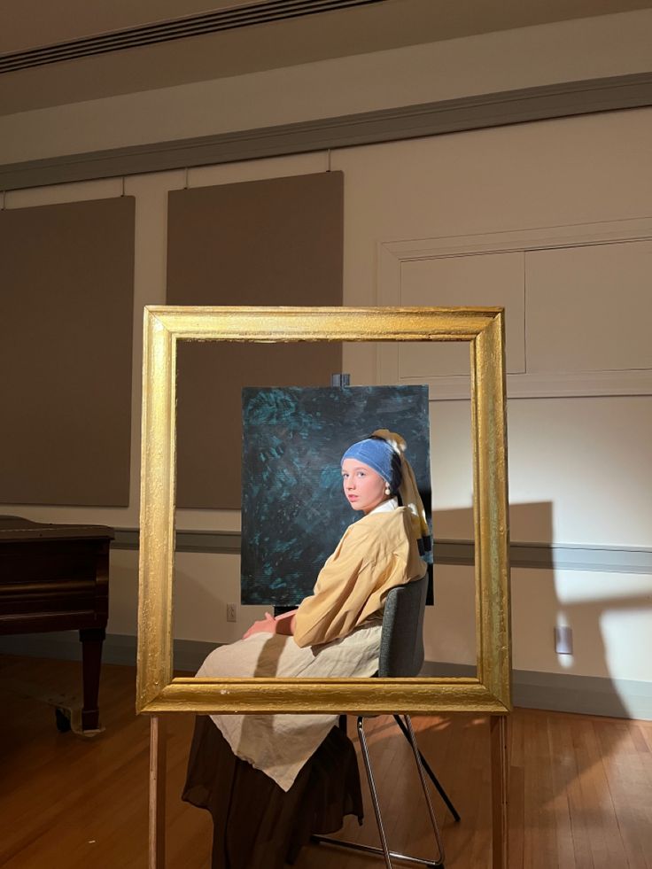 a woman with a pearl earring sitting in front of a painting on a easel