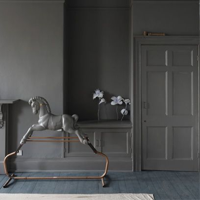 a white horse statue sitting on top of a wooden bench in a room with gray walls