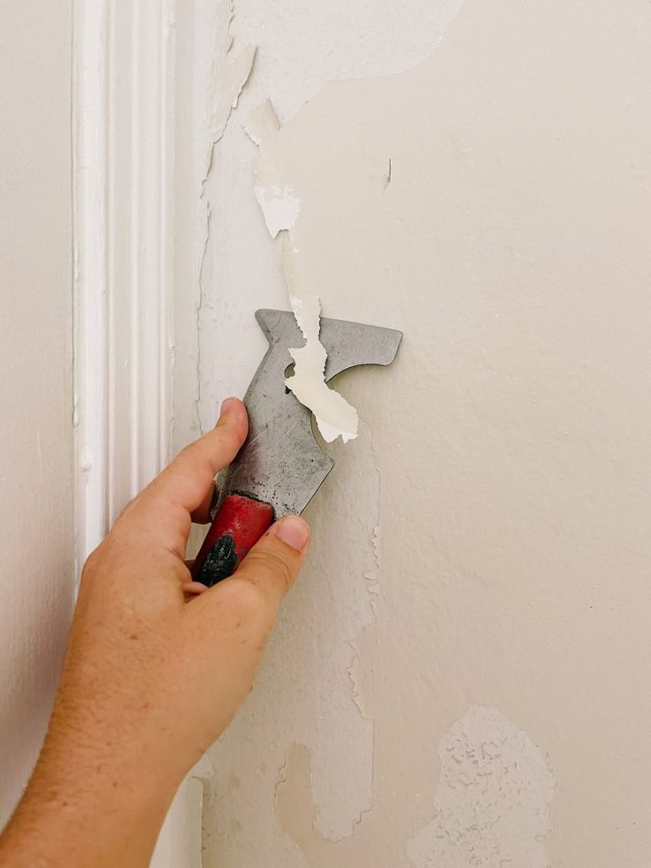 a person is holding a pair of pliers in front of a wall that has been torn off