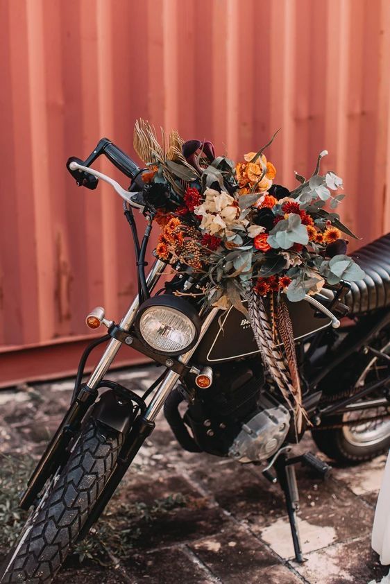 a motorcycle parked next to a red wall with flowers on the front wheel and back tire