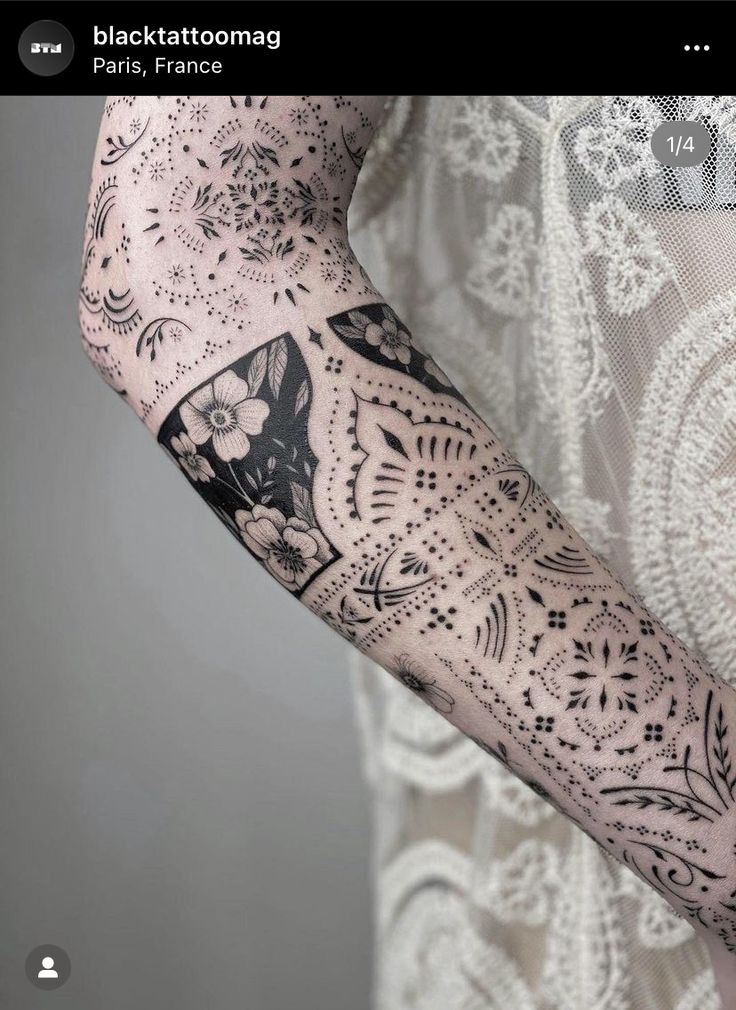 a woman's arm covered in black and white laces with flowers on it