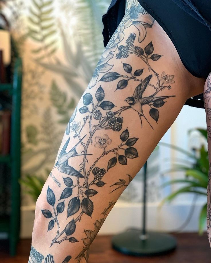 a woman's leg with tattoos and flowers on it