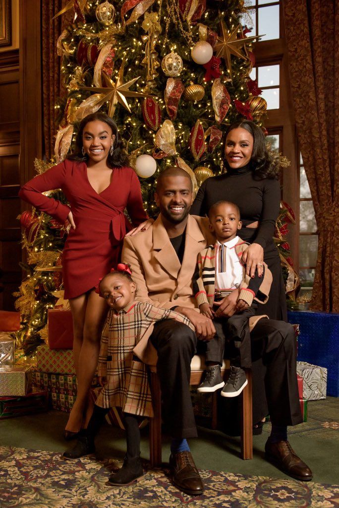 a family poses in front of a christmas tree