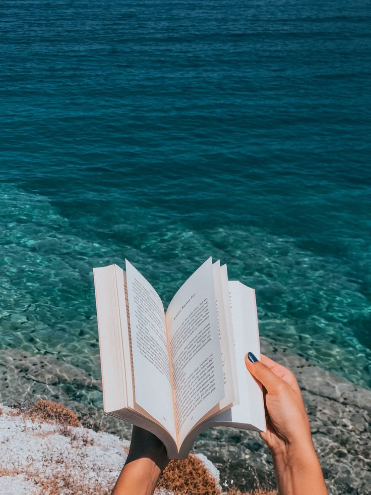 someone is reading a book on the beach