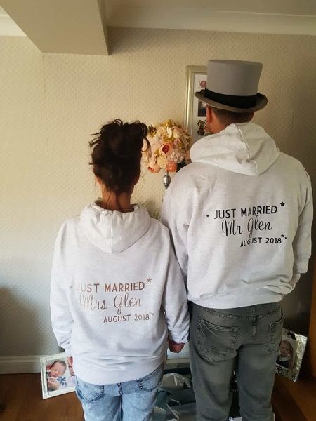 a man and woman standing next to each other in front of a mirror wearing matching hoodies