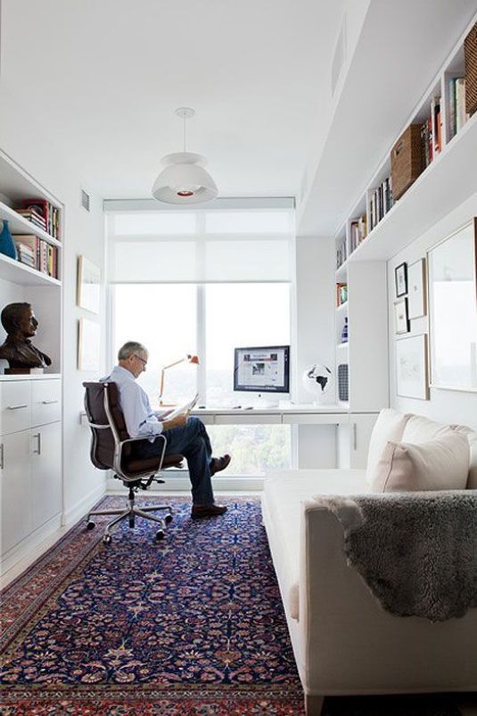 a man sitting at a desk in front of a computer on top of a rug