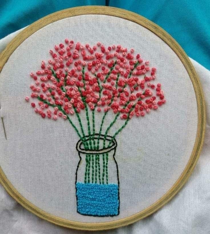 a vase with pink flowers in it sitting on top of a white cloth