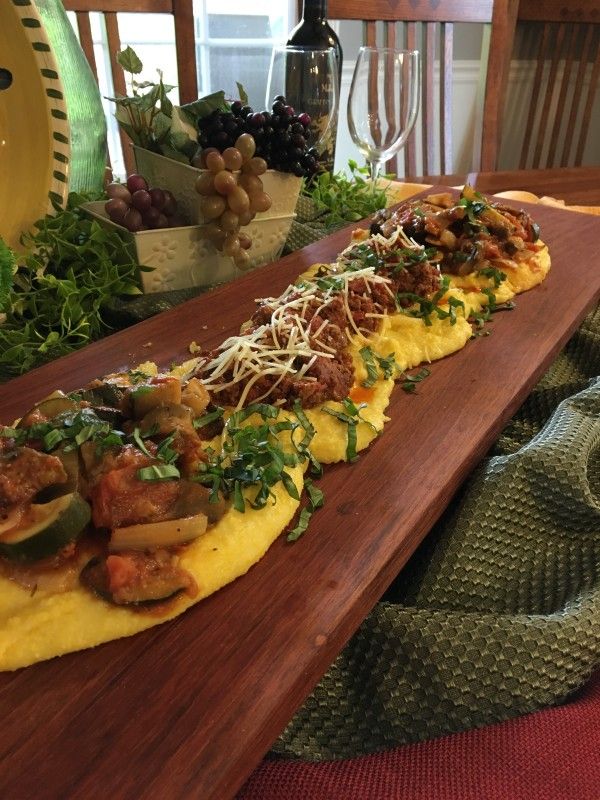 an omelet with meat, cheese and vegetables on a wooden platter sitting on a dining room table