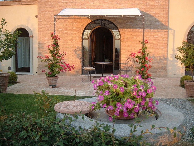 a patio with potted plants and flowers in the foreground, next to a brick building