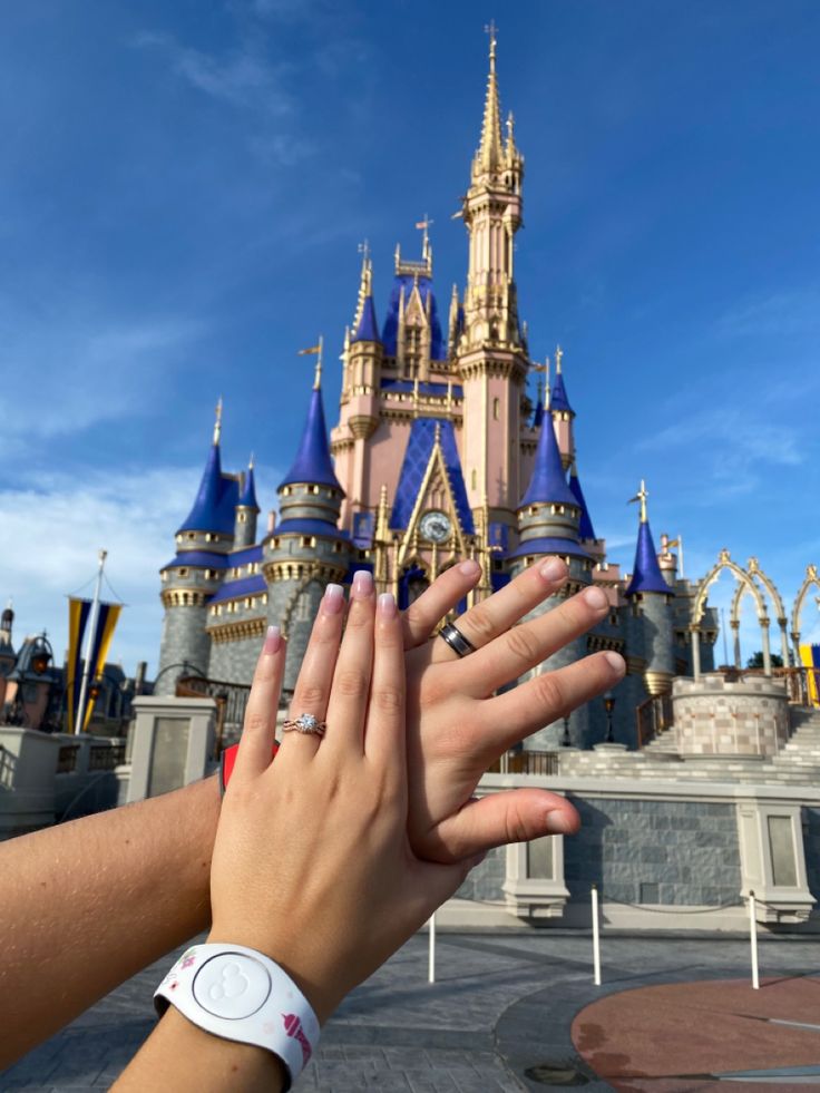 two hands reaching out to touch each other in front of a castle at disney world