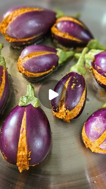 purple eggplant halves with orange peels on a metal plate