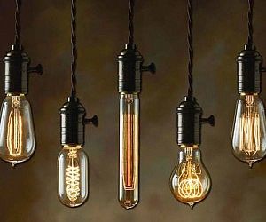 five light bulbs hanging from the ceiling with one bulb turned upside down and three are lit up