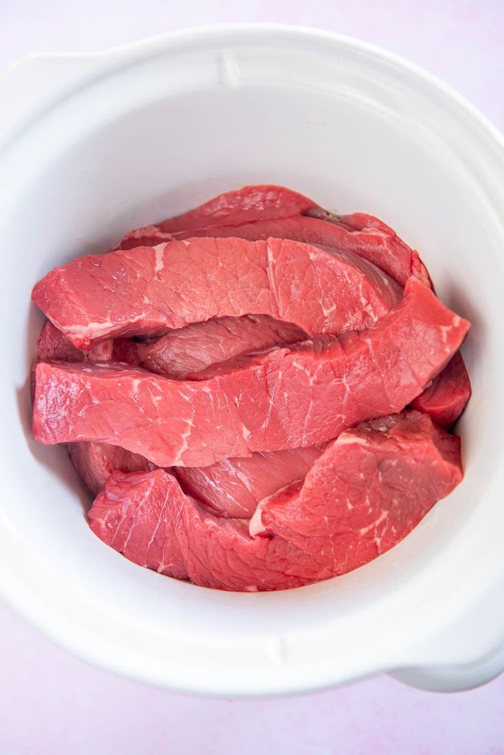 raw meat in a white bowl on a pink background