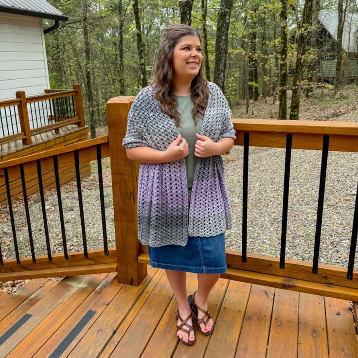 a woman standing on a wooden deck in front of a house and smiling at the camera