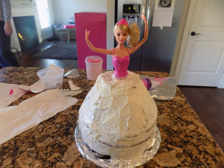 a barbie doll is standing on top of a cake that has been made with icing