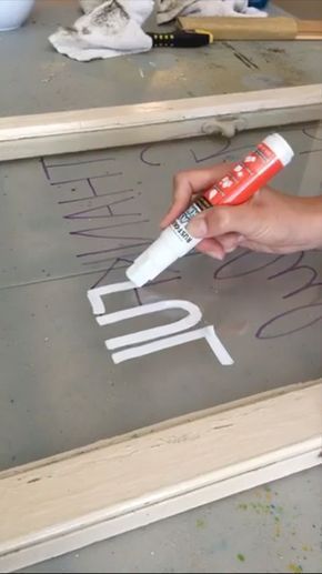 a person is painting the letters on a piece of wood with white paint and glue