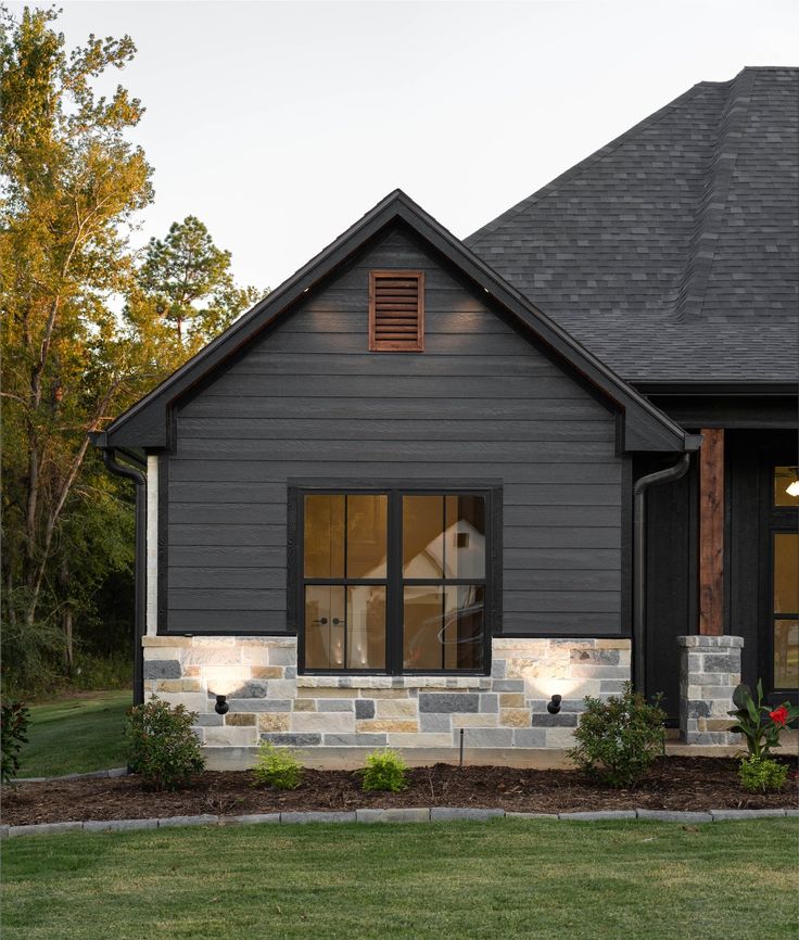 a gray house with black shutters and stone steps leading to the front door is shown