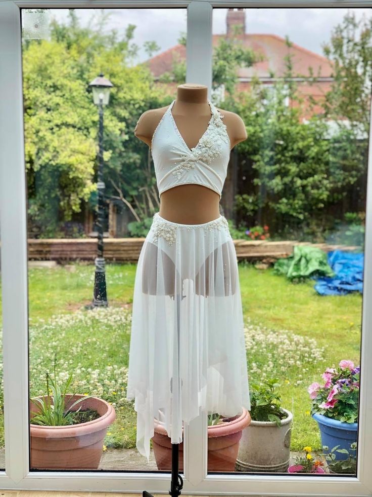 a woman's white skirt and crop top on display in front of a window