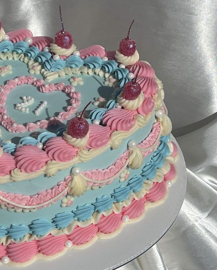 a heart shaped cake decorated with cherries and blue icing on a white platter