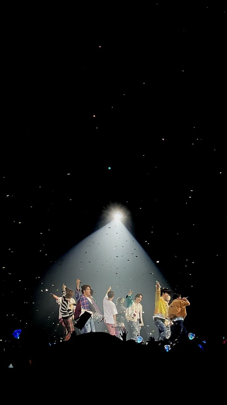 a group of people standing on top of a stage under a spotlight in the dark