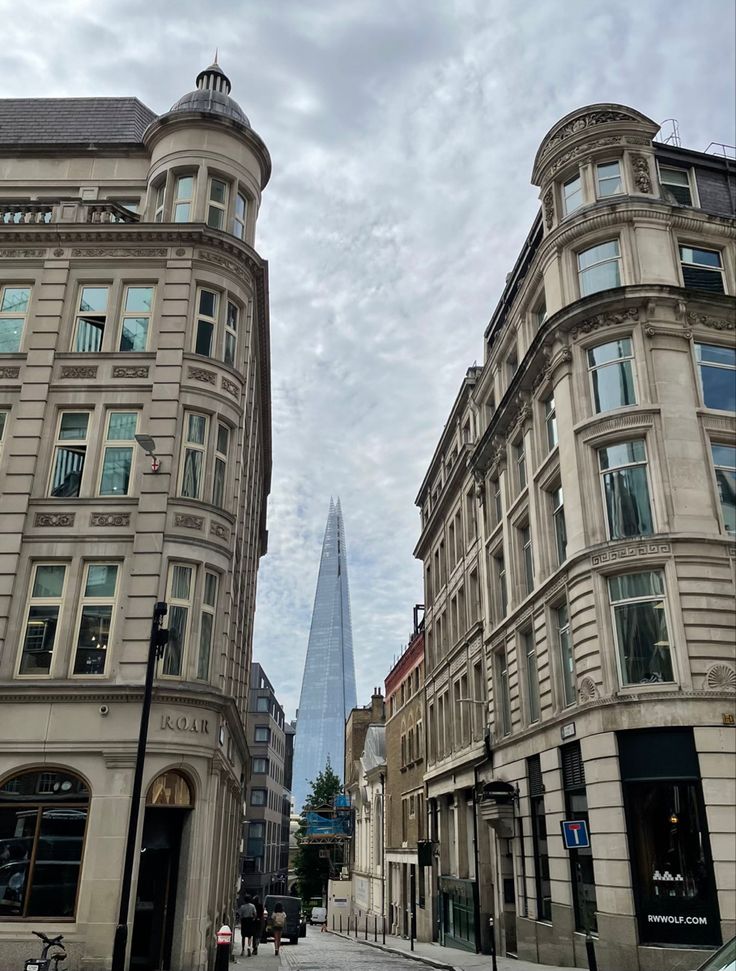 two tall buildings on the side of a street next to each other with a sky scraper in the background