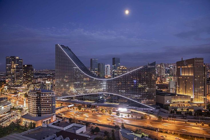 an aerial view of a city at night with the moon in the sky above it