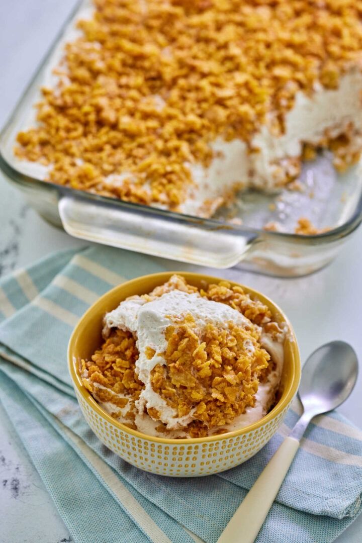 a dessert in a yellow bowl next to a glass dish filled with ice cream and granola