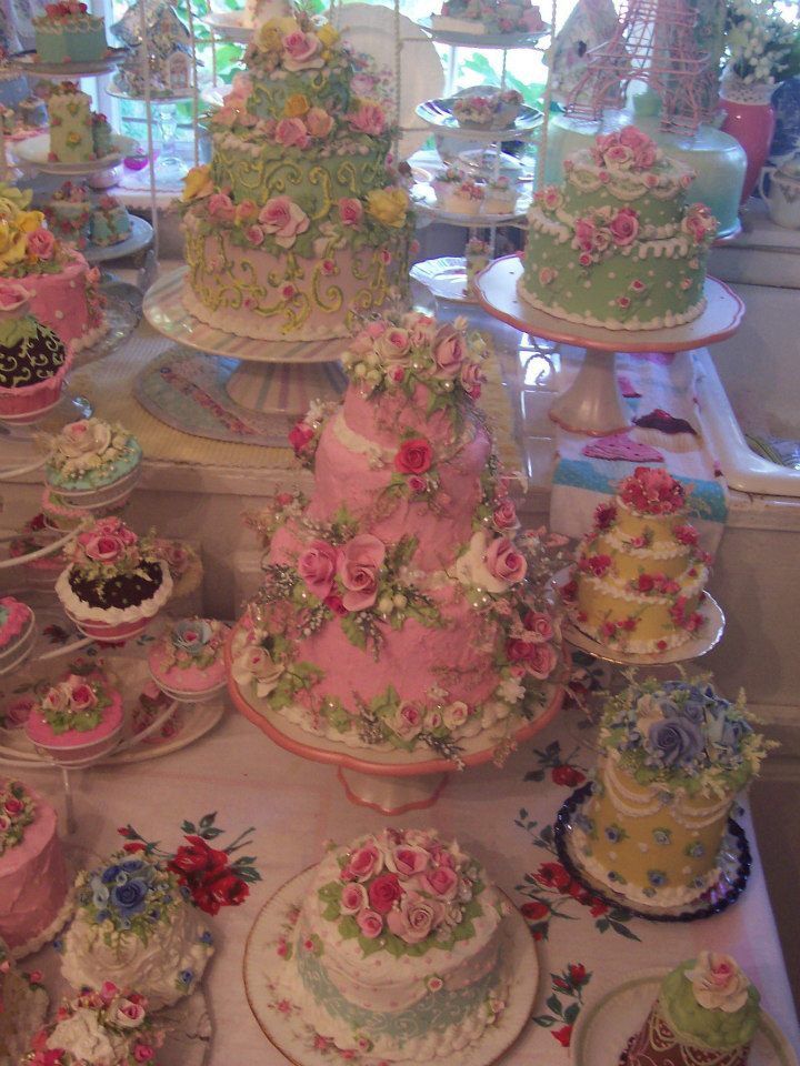 a table topped with lots of cakes and cupcakes on top of cake plates