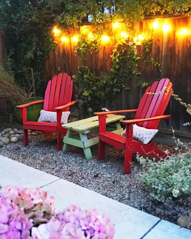 two red chairs sitting next to each other in front of a fence with lights on it