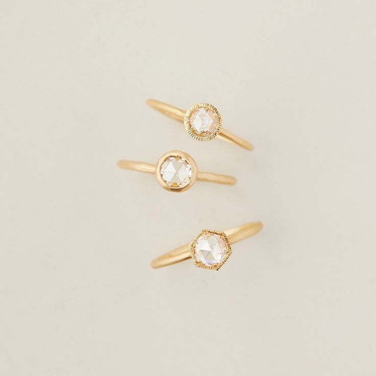 three gold rings with small white stones on each one, all in different shapes and sizes