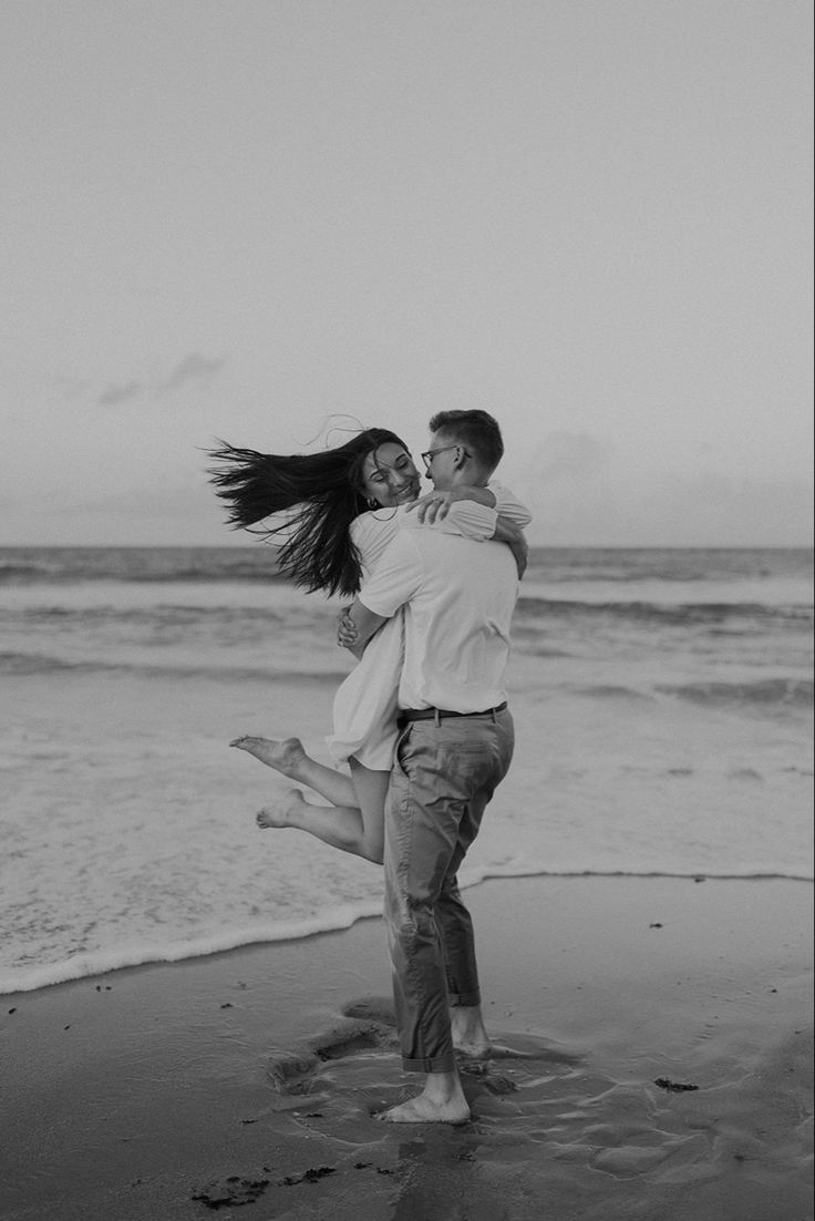 a man and woman are hugging on the beach