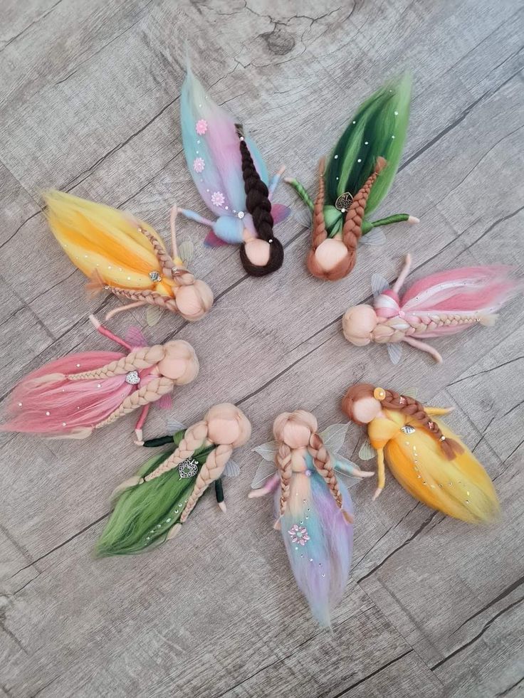 several fairy figurines arranged in a circle on a wooden surface with grass and flowers