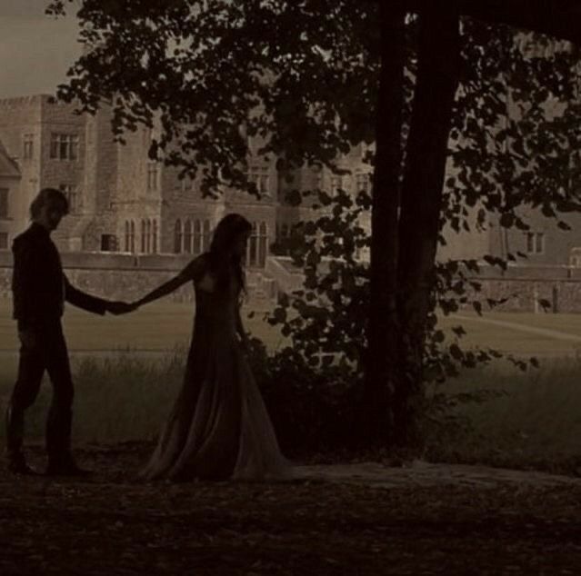 a man and woman holding hands in front of a tree