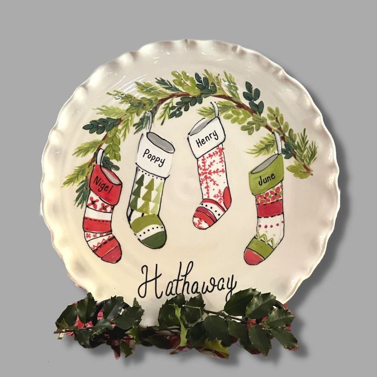 a plate with stockings on it and holly wreath around the edge that says, happy holidays