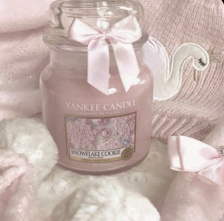 a pink candle sitting on top of a white teddy bear