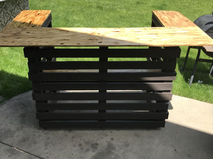 a table made out of wooden pallets sitting on top of a cement floor next to grass