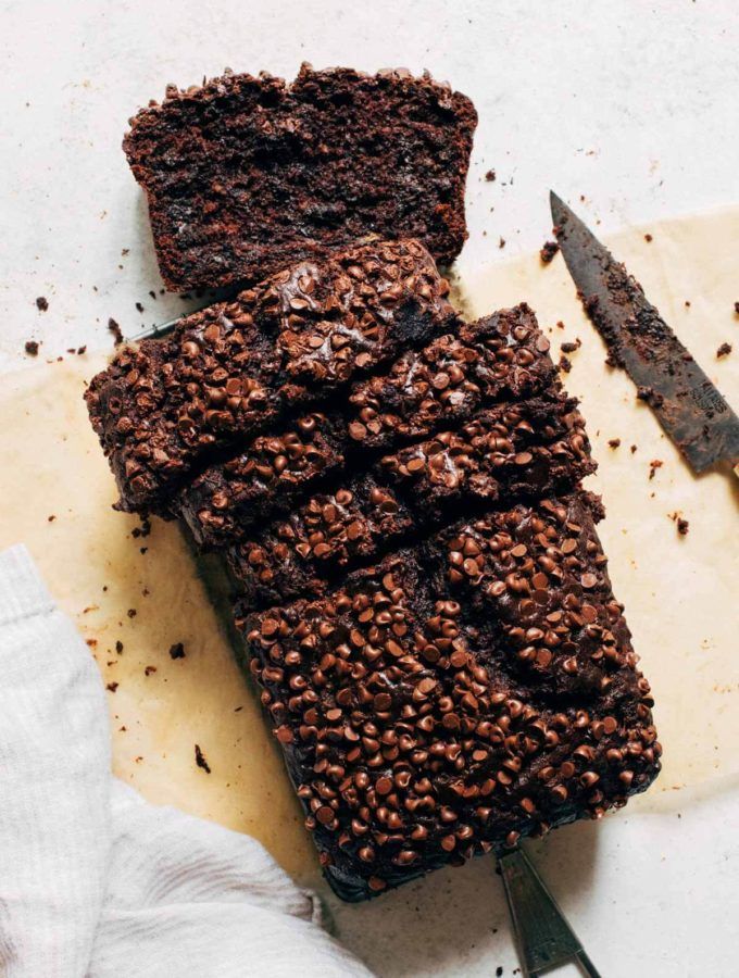 a loaf of chocolate cake sitting on top of a cutting board next to a knife