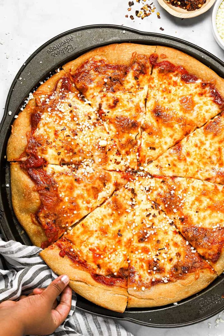 a pizza sitting in a pan on top of a table next to other food items