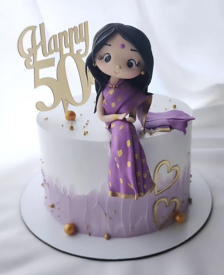 a purple and white birthday cake with a woman figurine sitting on the top