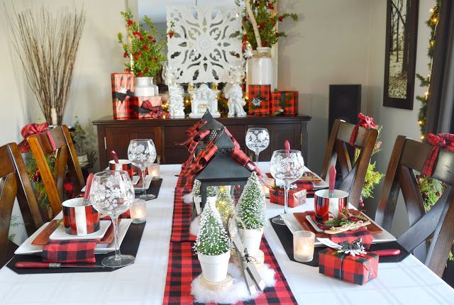 a dining room table set for christmas with red and black plaid napkins on it